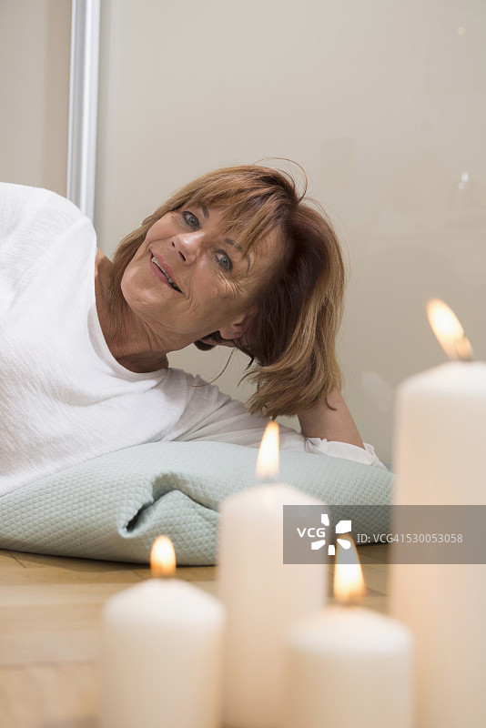 德国，巴伐利亚，慕尼黑，一名老年妇女躺在地板上，枕头上燃着蜡烛图片素材