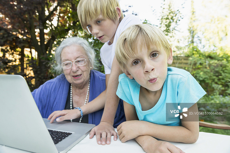 祖母和她的两个孙子用笔记本电脑图片素材