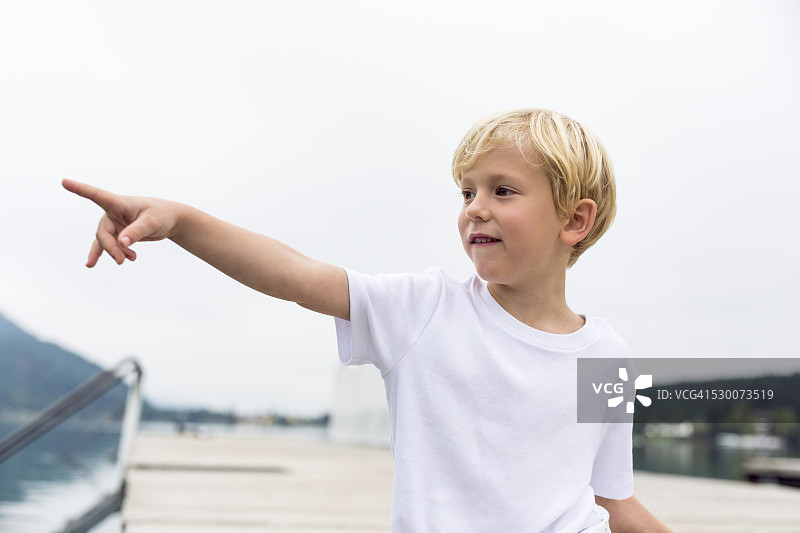 小男孩站在码头上指着什么东西的肖像图片素材