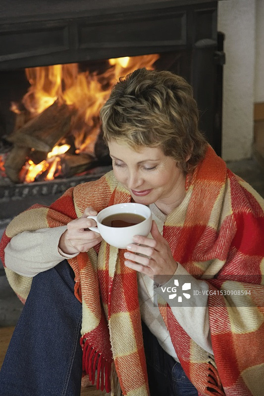 在壁炉边喝茶的女人图片素材