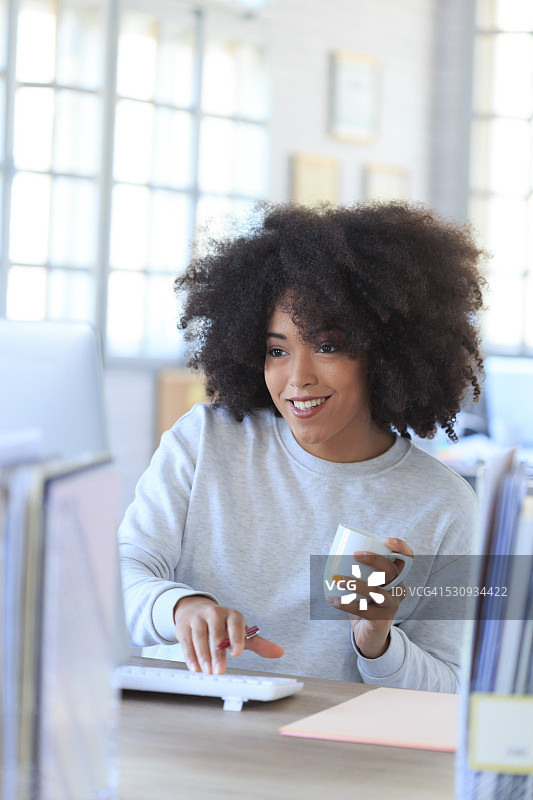 微笑的非洲式女商人喝着咖啡，用着电脑图片素材