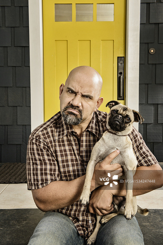 秃头男人抱着狗的肖像图片素材