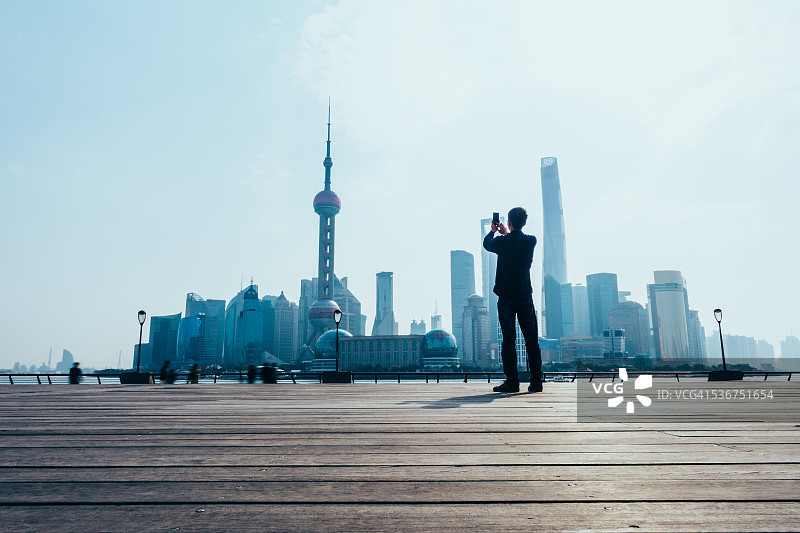 一个年轻人正在拍摄上海的天际线图片素材