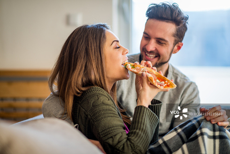 年轻夫妇在床上吃披萨图片素材