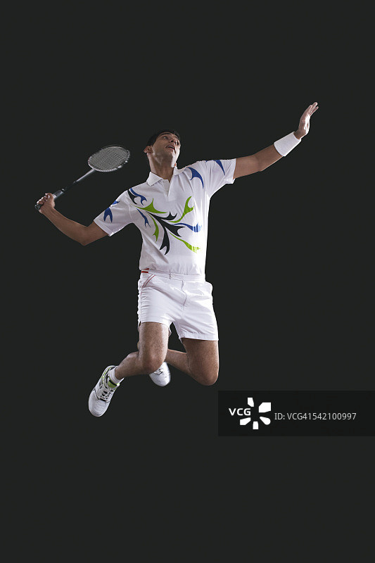 年轻的男性运动员拿着羽毛球拍在半空中跳跃图片素材