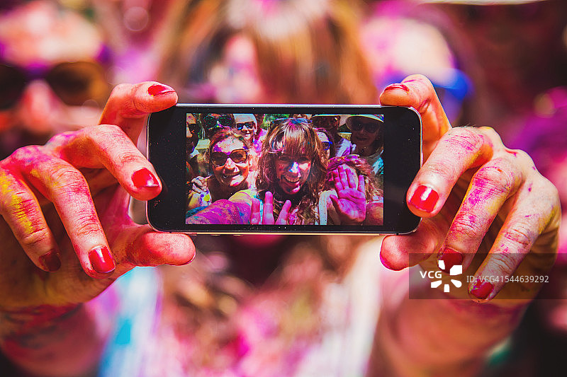 胡里节庆祝派对上，人们在户外集体自拍，脸上洋溢着幸福的表情，脸上覆盖着鲜艳的色彩。图片素材