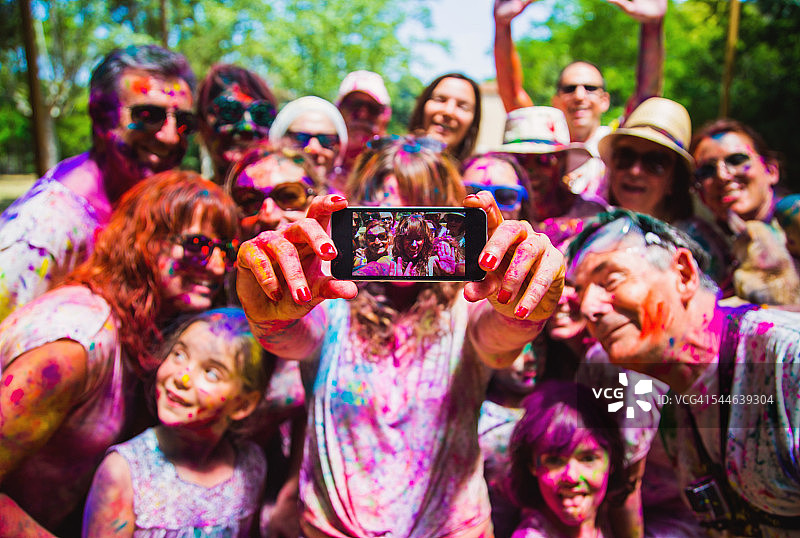 胡里节庆祝派对上，人们在户外集体自拍，脸上洋溢着幸福的表情，脸上覆盖着鲜艳的色彩。图片素材