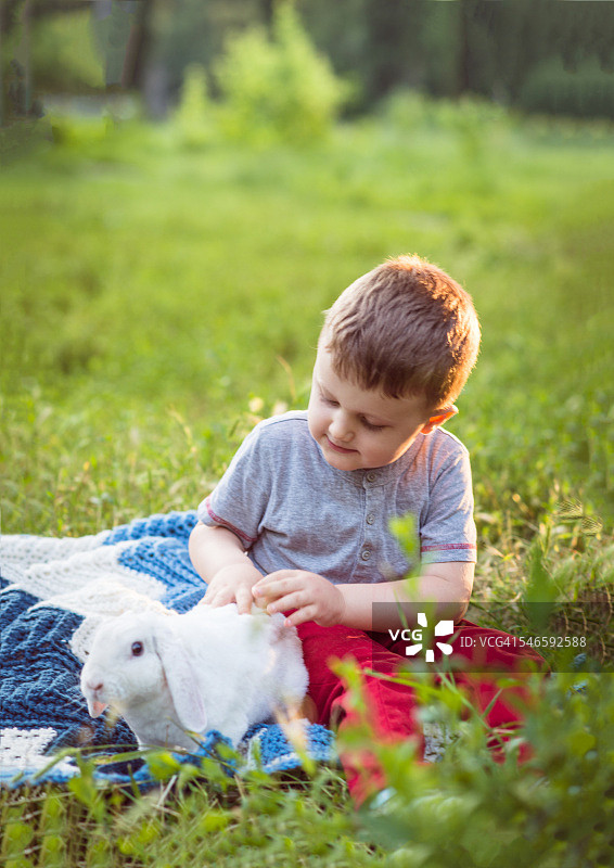 小男孩和白色复活节兔子坐在一起图片素材