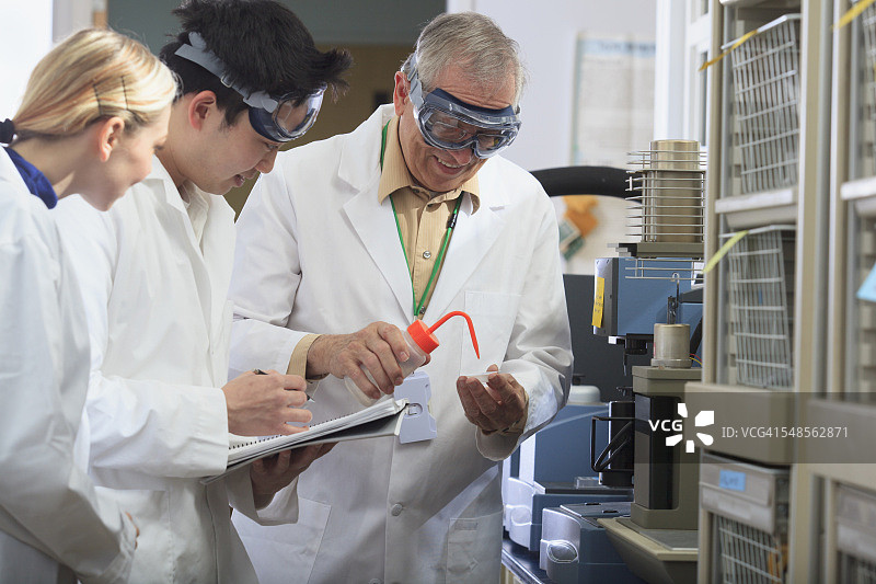 教授与工程学生在实验室向样品盘中添加乙醇图片素材