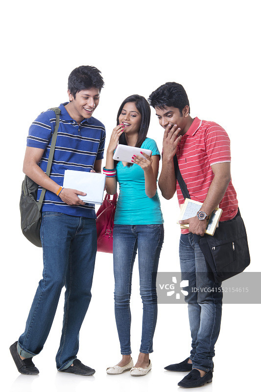 在白色背景下使用数码平板电脑的快乐大学朋友图片素材