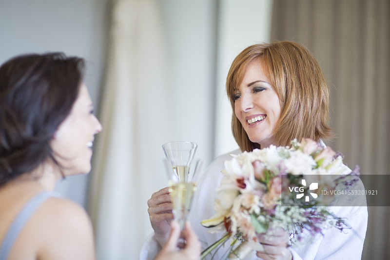 新娘和伴娘在准备婚礼时碰杯庆祝图片素材