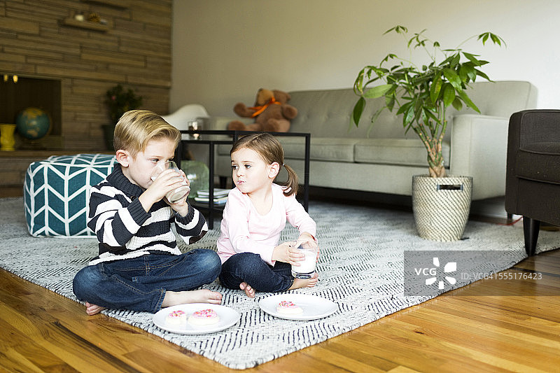 美国犹他州盐湖城，哥哥(6-7)和姐姐(4-5)在客厅地板上喝牛奶图片素材