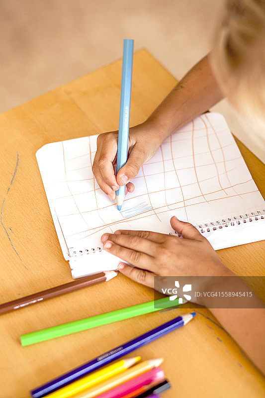 裁剪图像的女孩在教室里用彩色铅笔画画图片素材