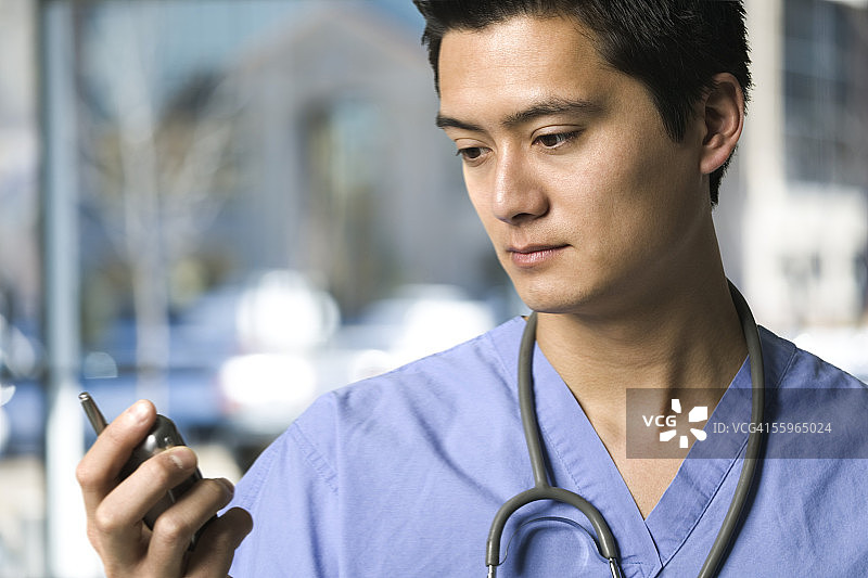 一个男性医生拿着手机的特写图片素材