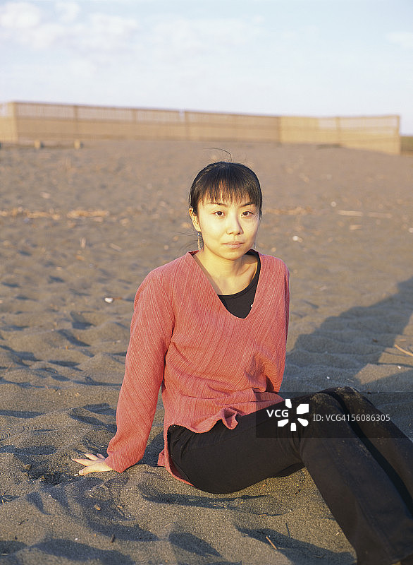 一个年轻的女人坐在海滩上图片素材