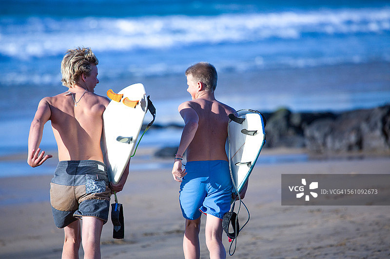 西班牙富埃特文图拉，两名少年冲浪者向大海奔跑图片素材