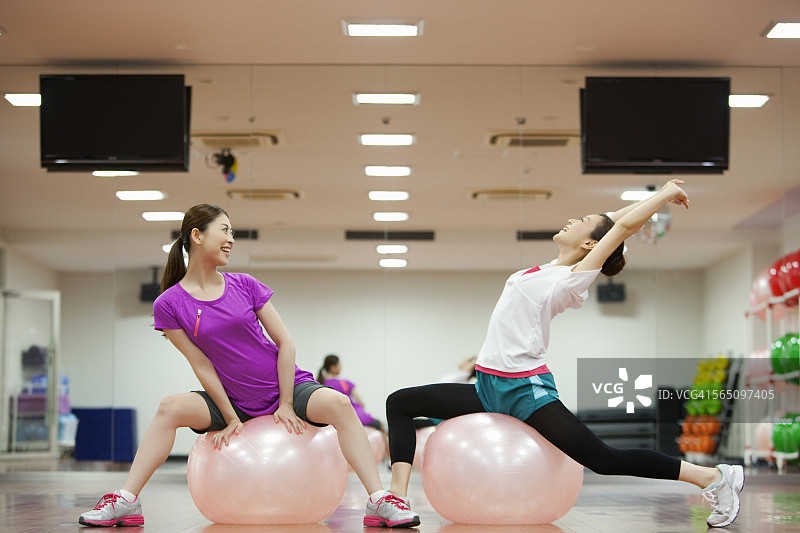 两个女人在健身房里的健身球上锻炼图片素材