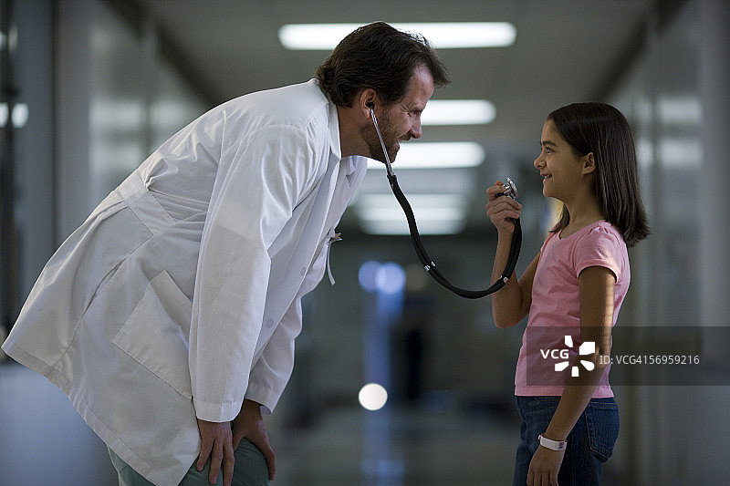 一个女孩对着男医生的听诊器说话图片素材