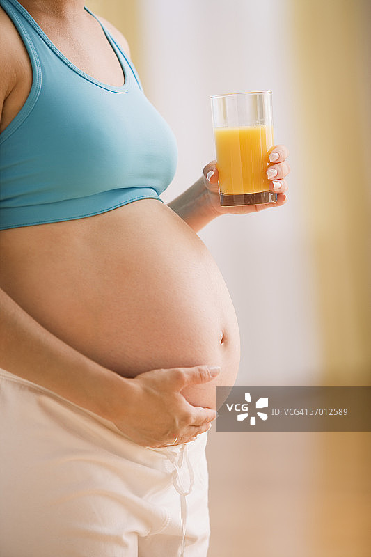 孕妇抱着肚子喝着果汁图片素材