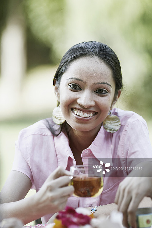 一个十几岁的女孩拿着一杯茶微笑的特写图片素材