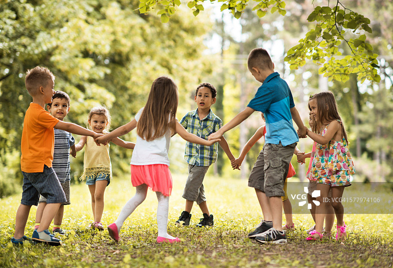 一群孩子在公园里玩围玫瑰圈游戏。图片素材