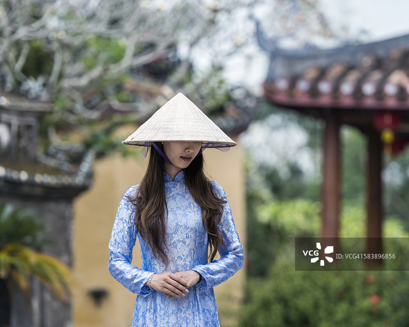 越南广南中南部海岸会安，穿着奥代服装和锥形帽子的年轻成年妇女肖像图片素材