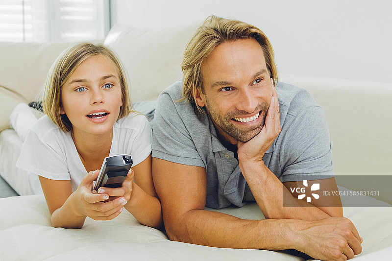 父亲和女儿躺在沙发上看电视图片素材