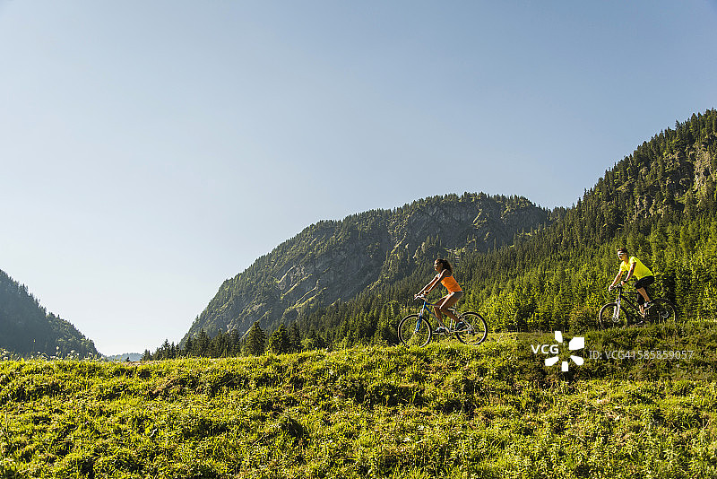 奥地利，蒂罗尔，坦海姆山谷，一对年轻夫妇在高山风景中骑山地车图片素材