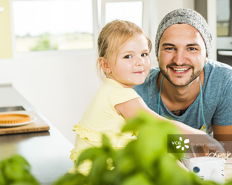 微笑的父亲和女儿在厨房烘焙的肖像图片素材