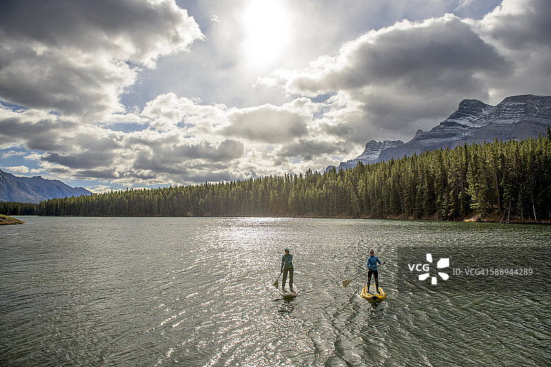 两名妇女用桨划过山湖图片素材
