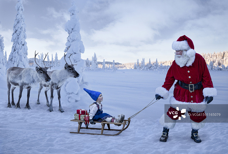 圣诞老人用驯鹿拉着一个女孩的雪橇图片素材
