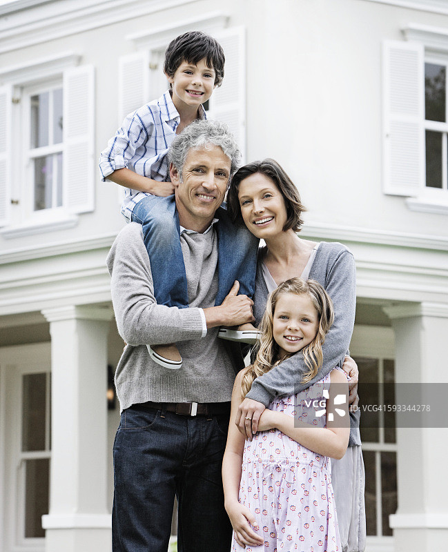 一家人微笑着站在房子前面图片素材