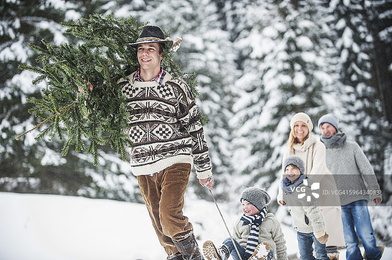 奥地利，在冬天的森林里，一个人带着圣诞树和家人在一起图片素材