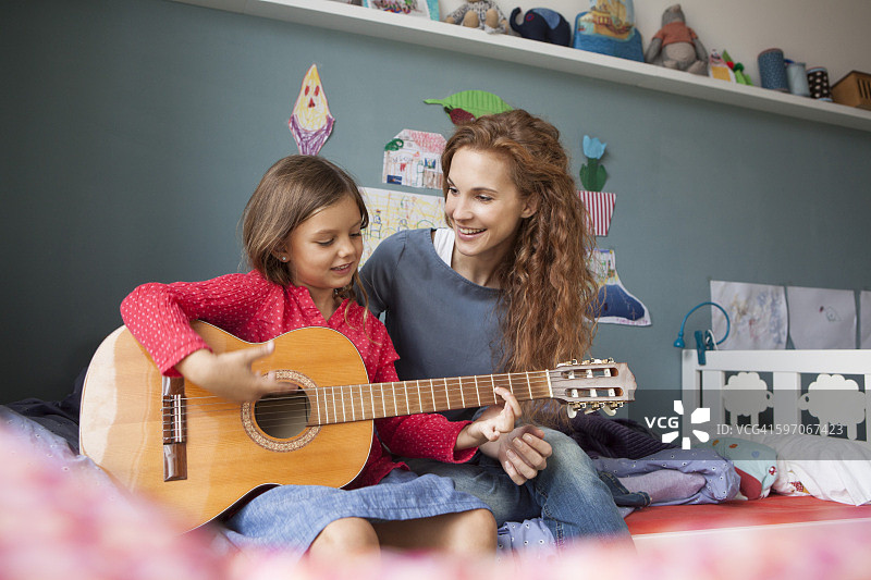 小女孩弹吉他，她妈妈在听图片素材