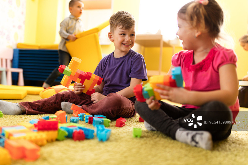 小男孩和小女孩在幼儿园玩玩具积木。图片素材