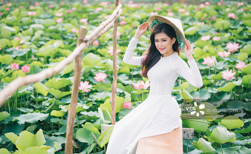 越南年轻女子穿着傲黛长裙在美丽的荷塘里图片素材