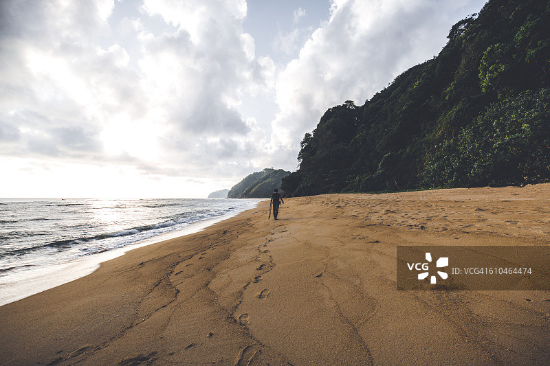一个人沿着美丽的海滩散步，只有大自然陪伴。图片素材