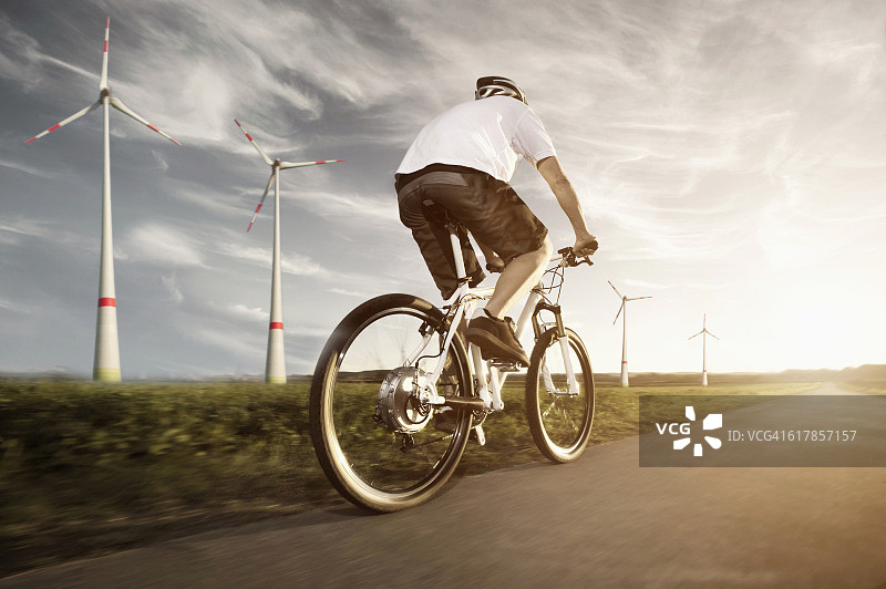 “日落时分，德国巴伐利亚，一名成熟男子骑着装有风力发电机的电动自行车”图片素材