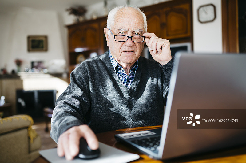一个在家里用笔记本电脑的老人的肖像图片素材