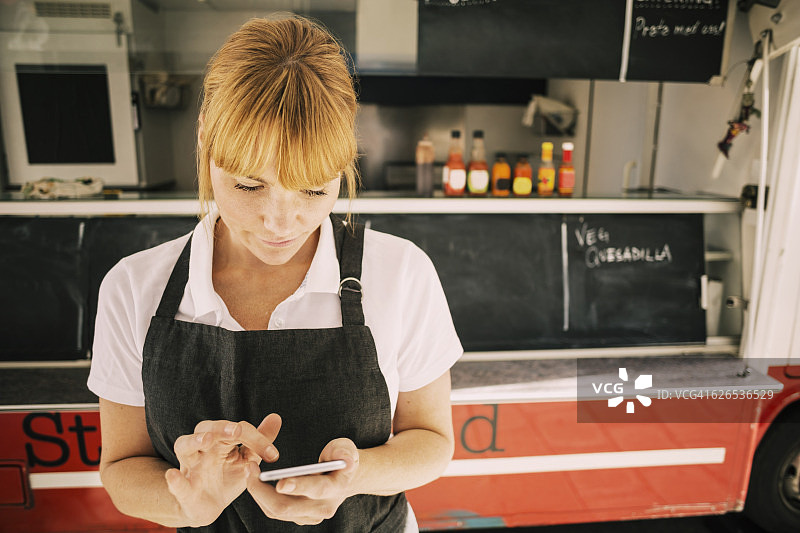 女厨师用手机对抗餐车的特写图片素材