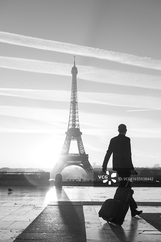 旅行家提着旅行箱走在巴黎埃菲尔铁塔上图片素材
