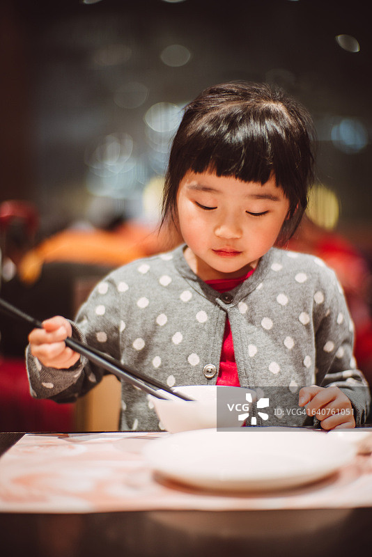 可爱的小女孩用筷子吃饭图片素材