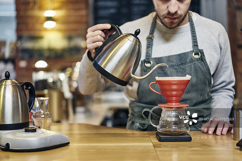 咖啡师在咖啡店将开水倒入咖啡过滤器图片素材