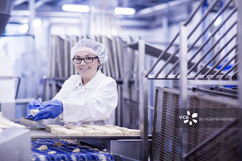 在食品生产厂工作的妇女微笑着看着镜头图片素材