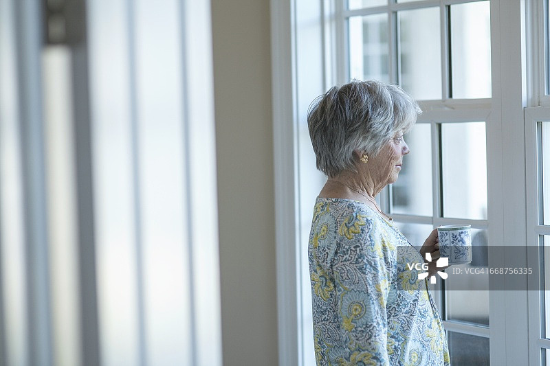一位老妇人站在窗边的肖像图片素材