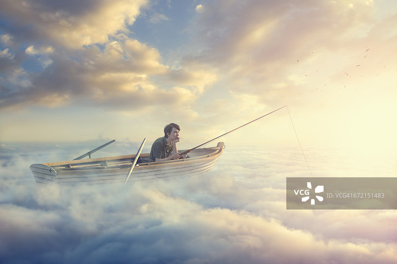 一个白人男孩在云中划着小船钓鱼图片素材