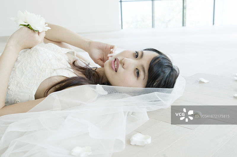 日本新娘用花瓣躺在地上，侧视图片素材