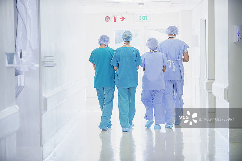 四名穿着手术服的医护人员走在医院走廊的后视图图片素材