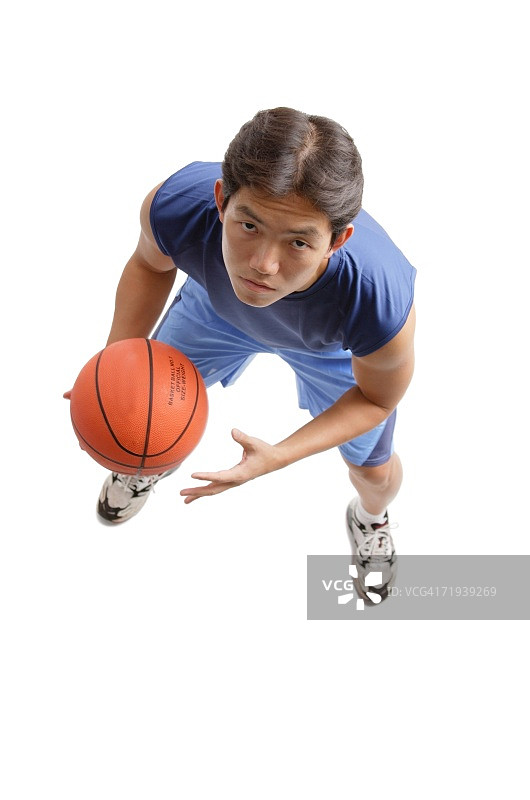一个年轻人拿着篮球，抬头看着镜头图片素材