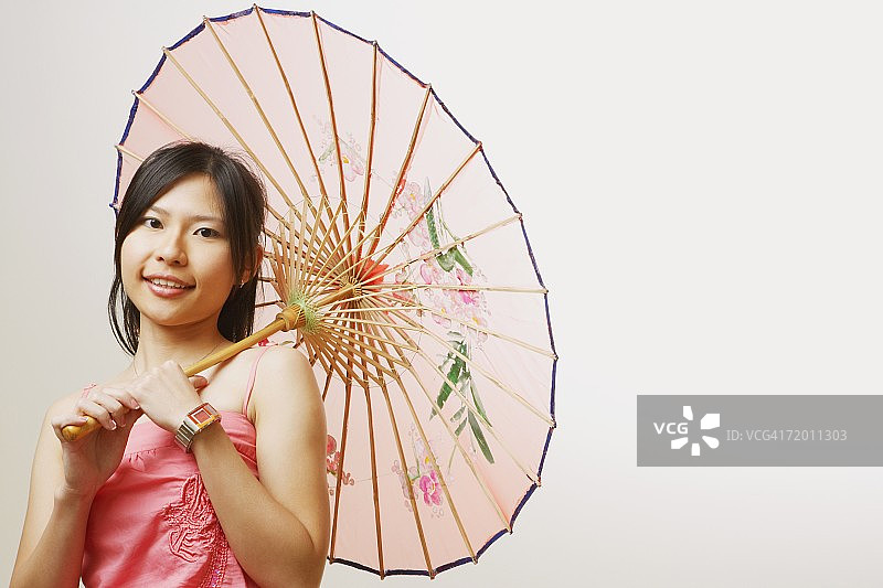 一个年轻女子的肖像拿着一把阳伞和微笑图片素材